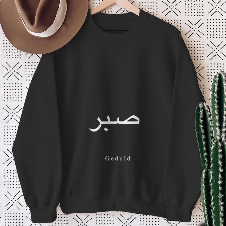 Geduld Sweatshirt Unisex Schwarz, Schriftzug in Deutsch und Arabisch Geschenke für alte Frauen